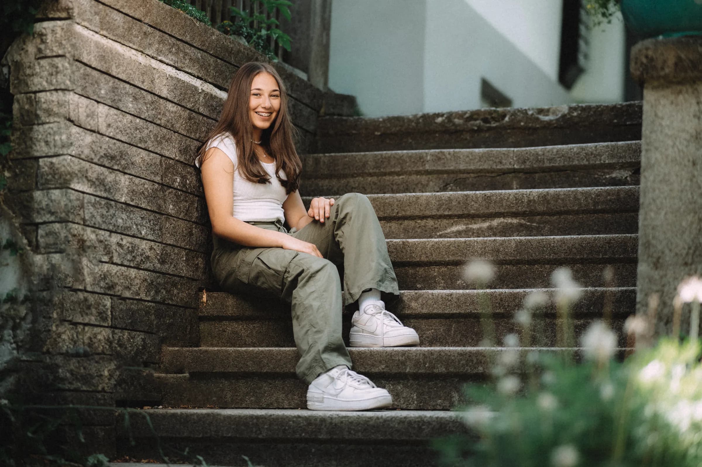 Junge Frau sitzt lachend auf einer Steintreppe