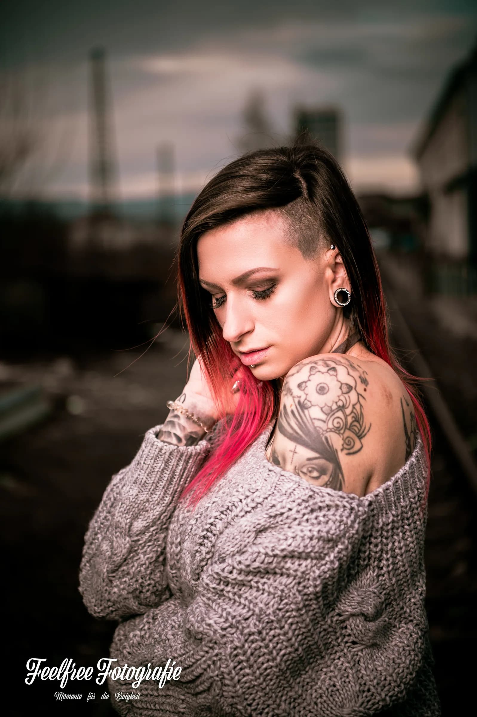 Frau mit Tattoos und Strickpullover in urbaner Umgebung