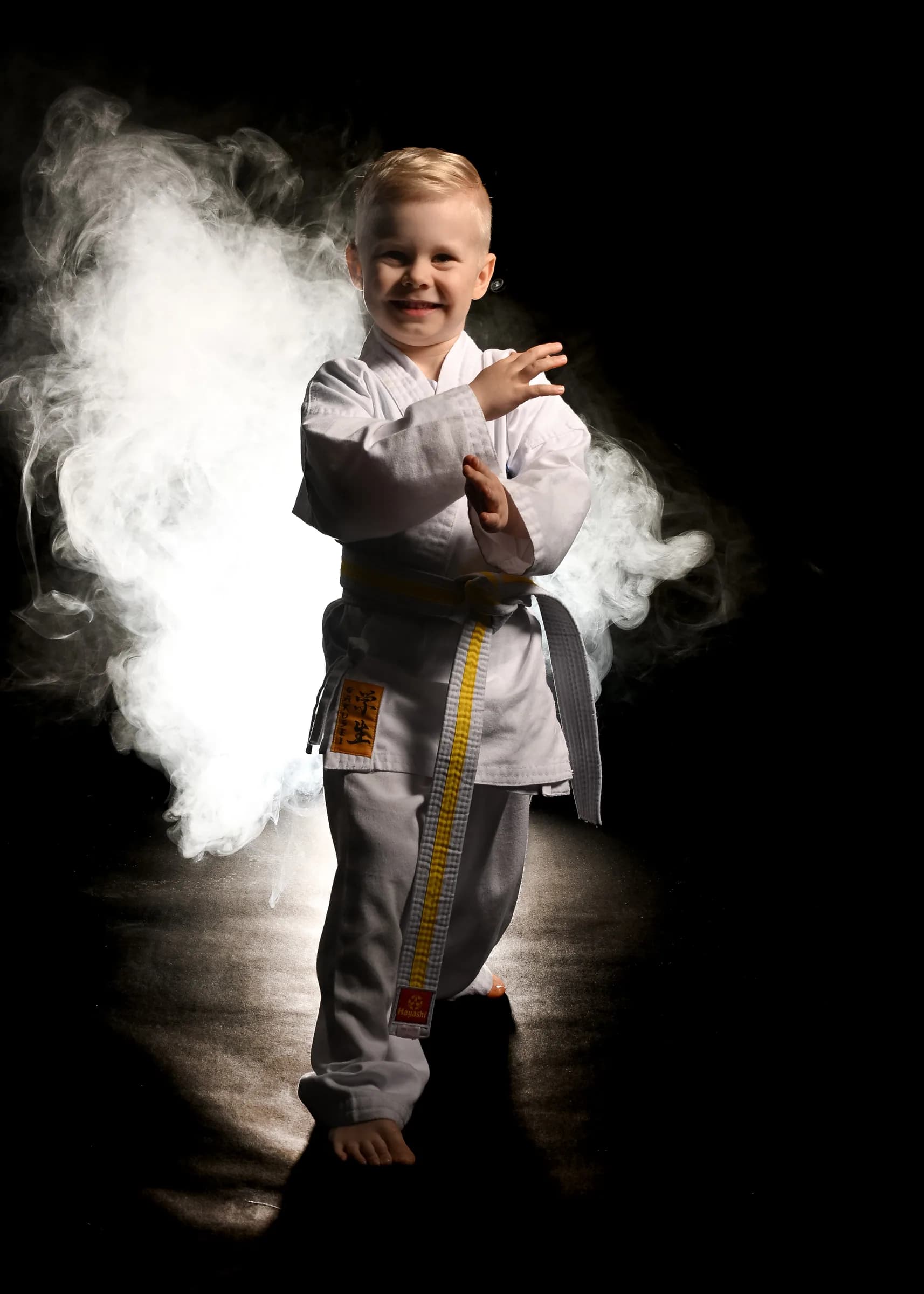 Junge im Karateanzug mit Nebel im Studio