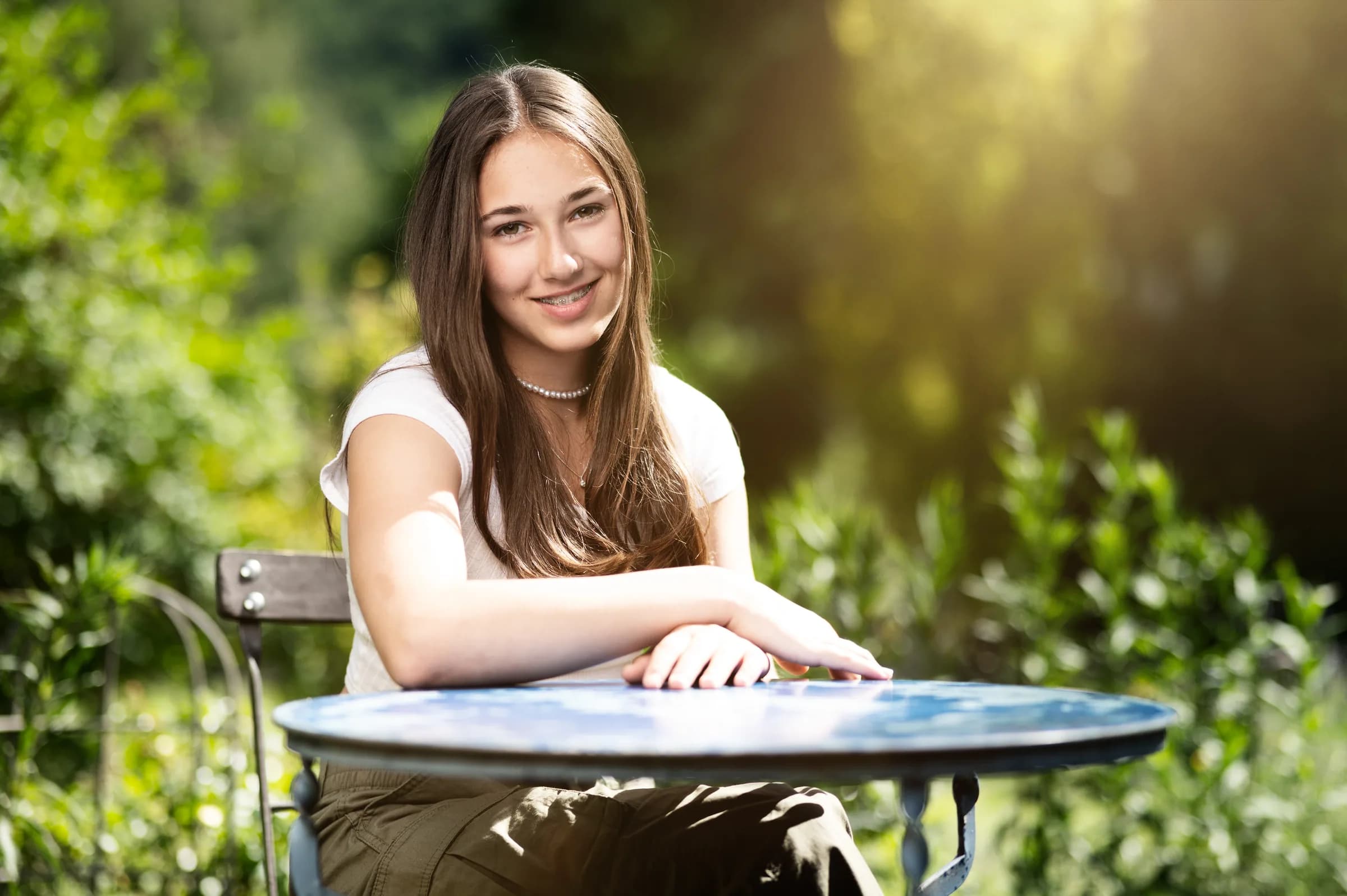 Junge Frau am Gartentisch im weichen Sonnenlicht