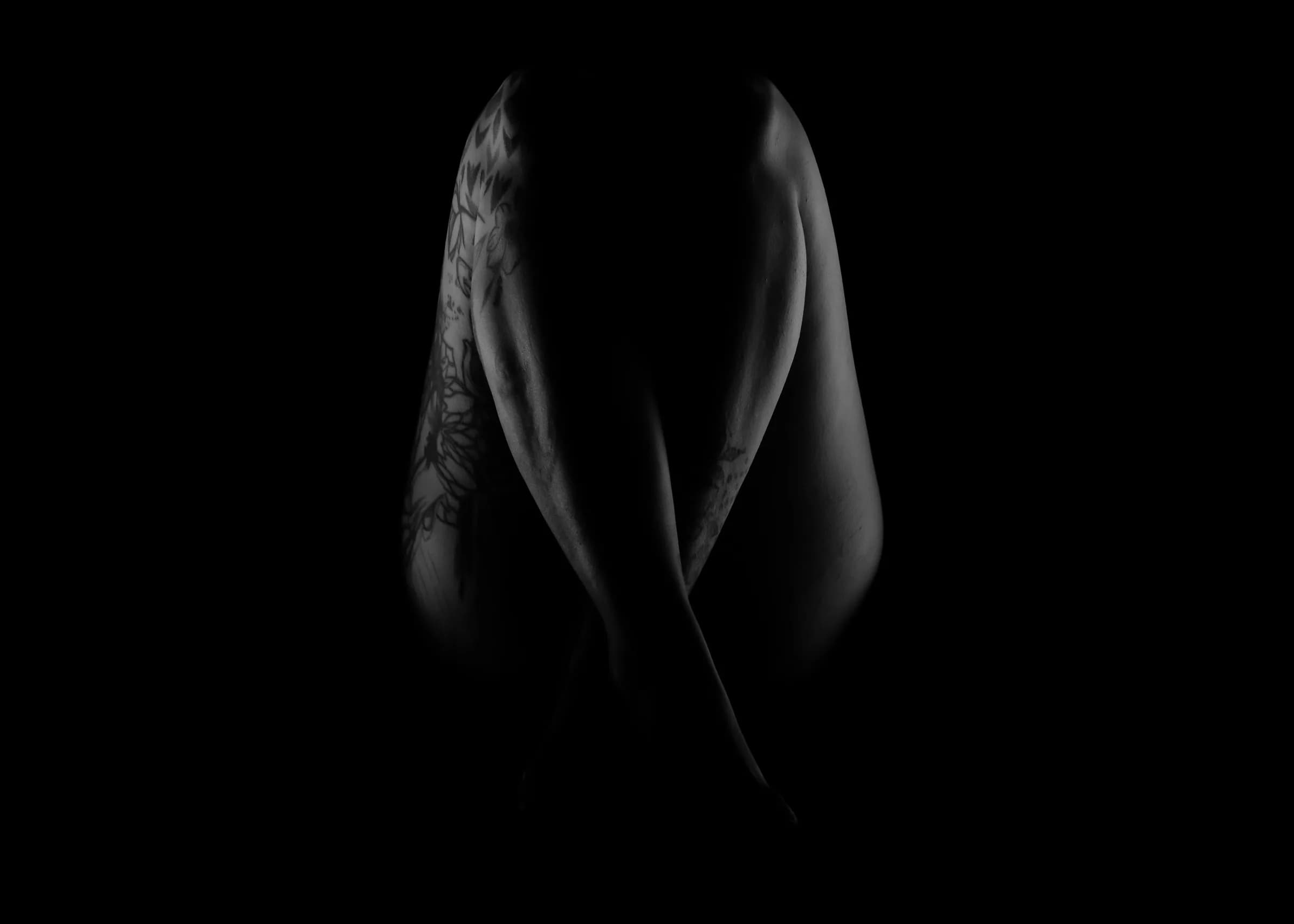 Bodyscape in Schwarz-Weiß: Rücken mit Tattoo im Streiflicht