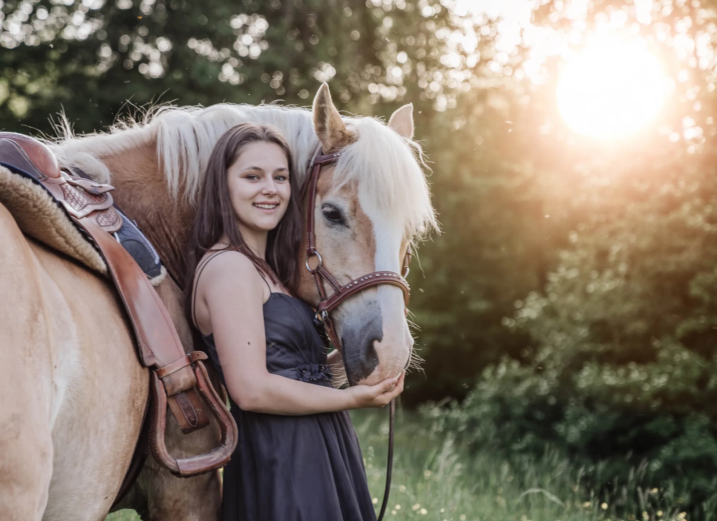 Junge Frau schmiegt sich an ihren Haflinger im Abendlicht